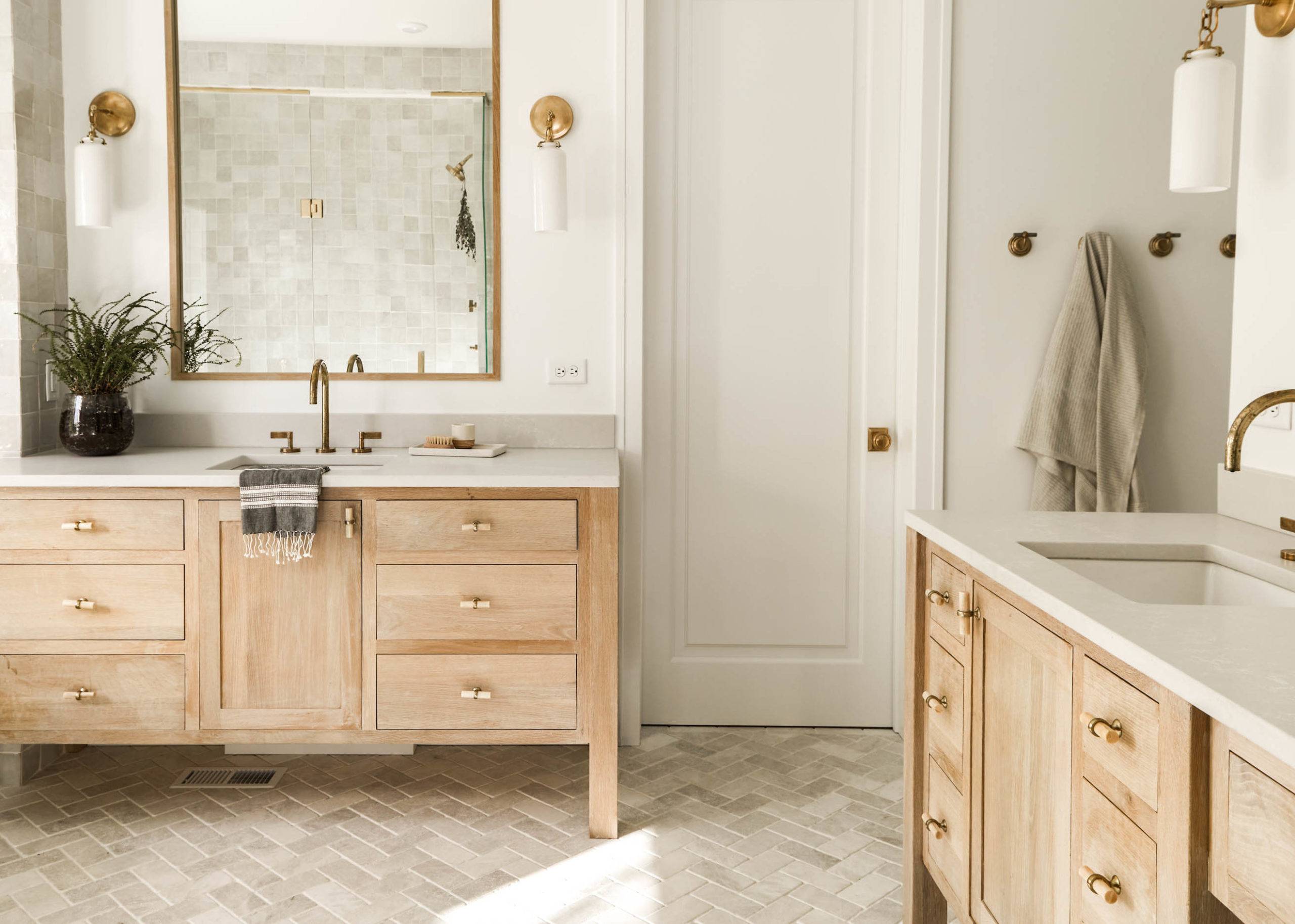 Large minimalist bathroom with marble herringbone tile flooring and light wood vanities