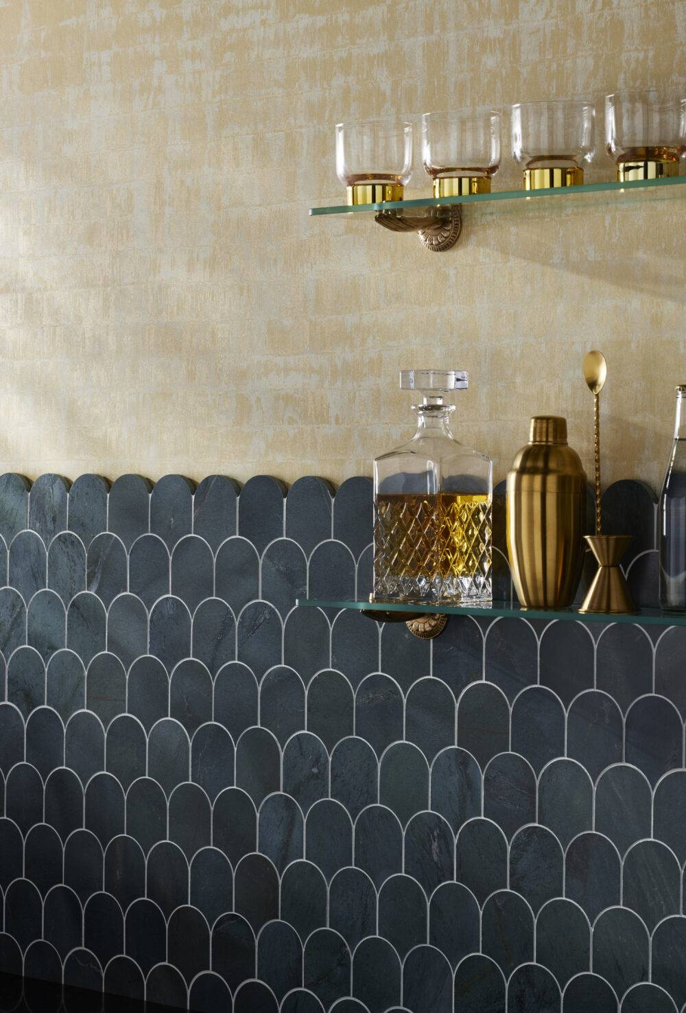 Scalloped tile half wall with glass shelves with glasses and bar items. 
