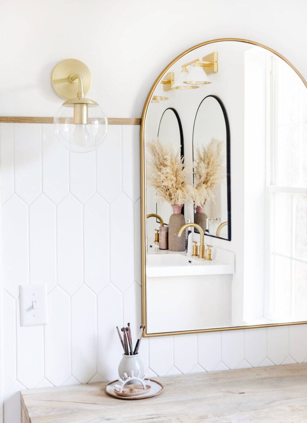 Bathroom with white picket tile wall and gold mirror. 