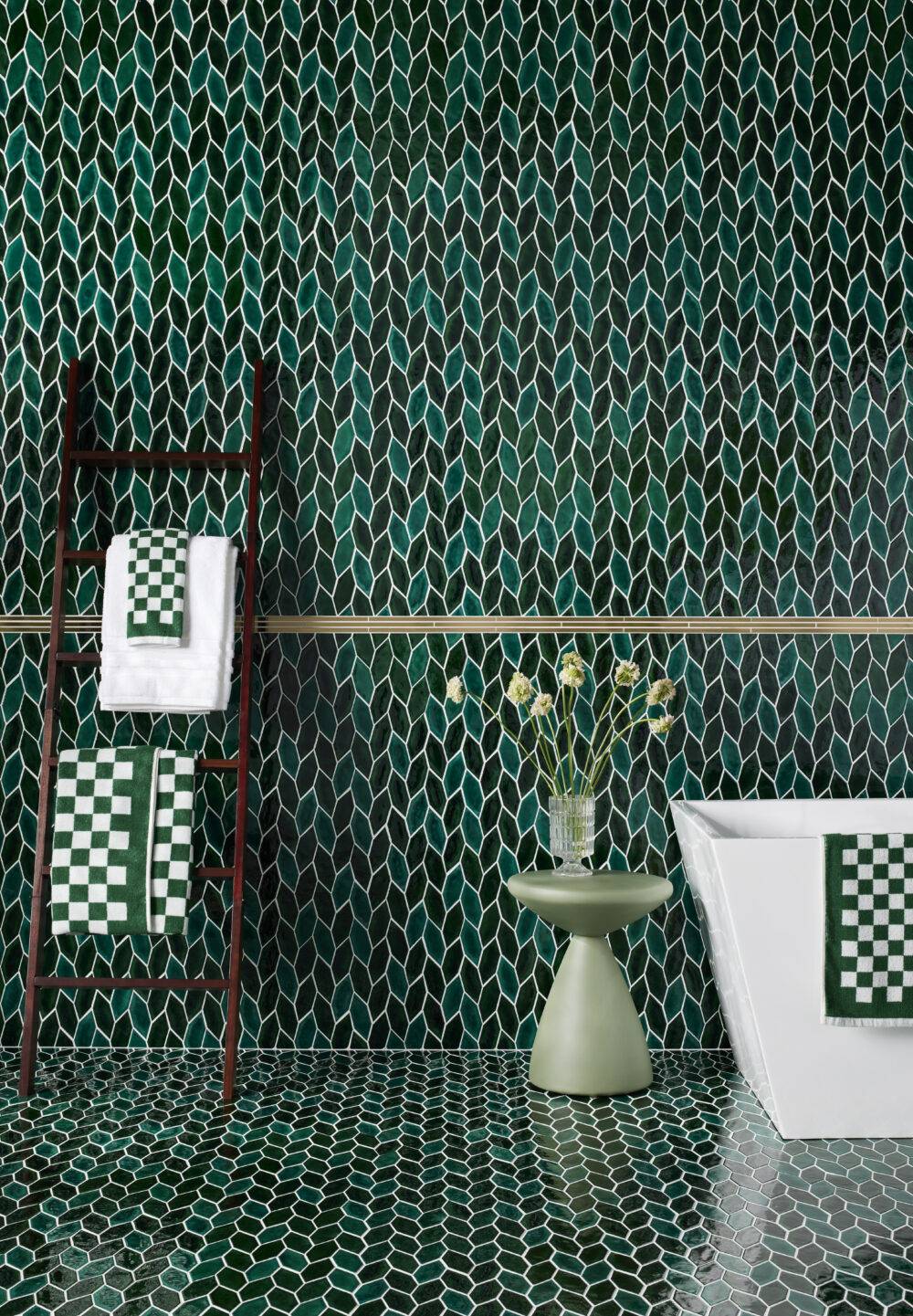 Green leaf mosaic bathroom wall with ladder towel rack. 