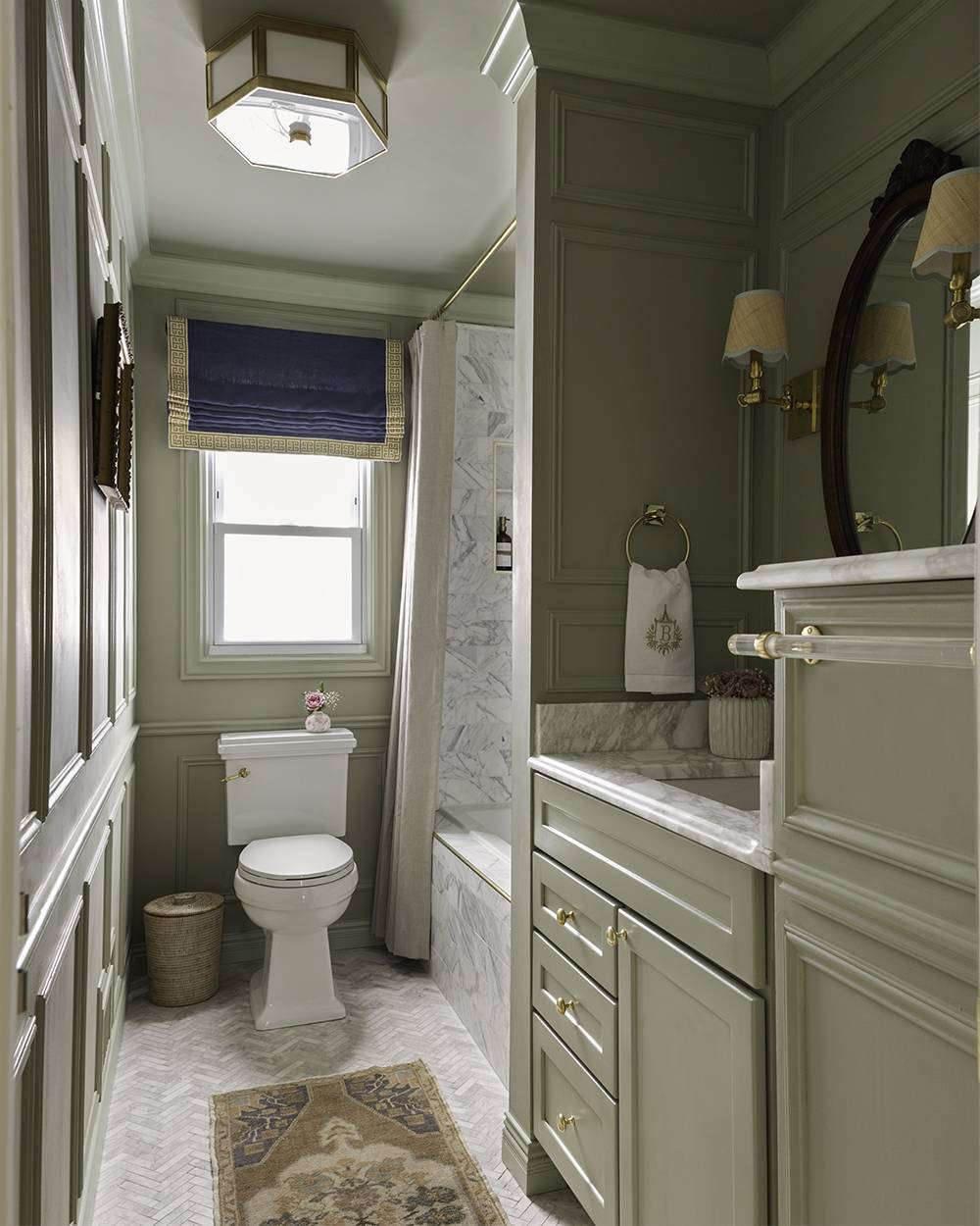 Luxurious bathroom with sage green cabinetry and white marble shower