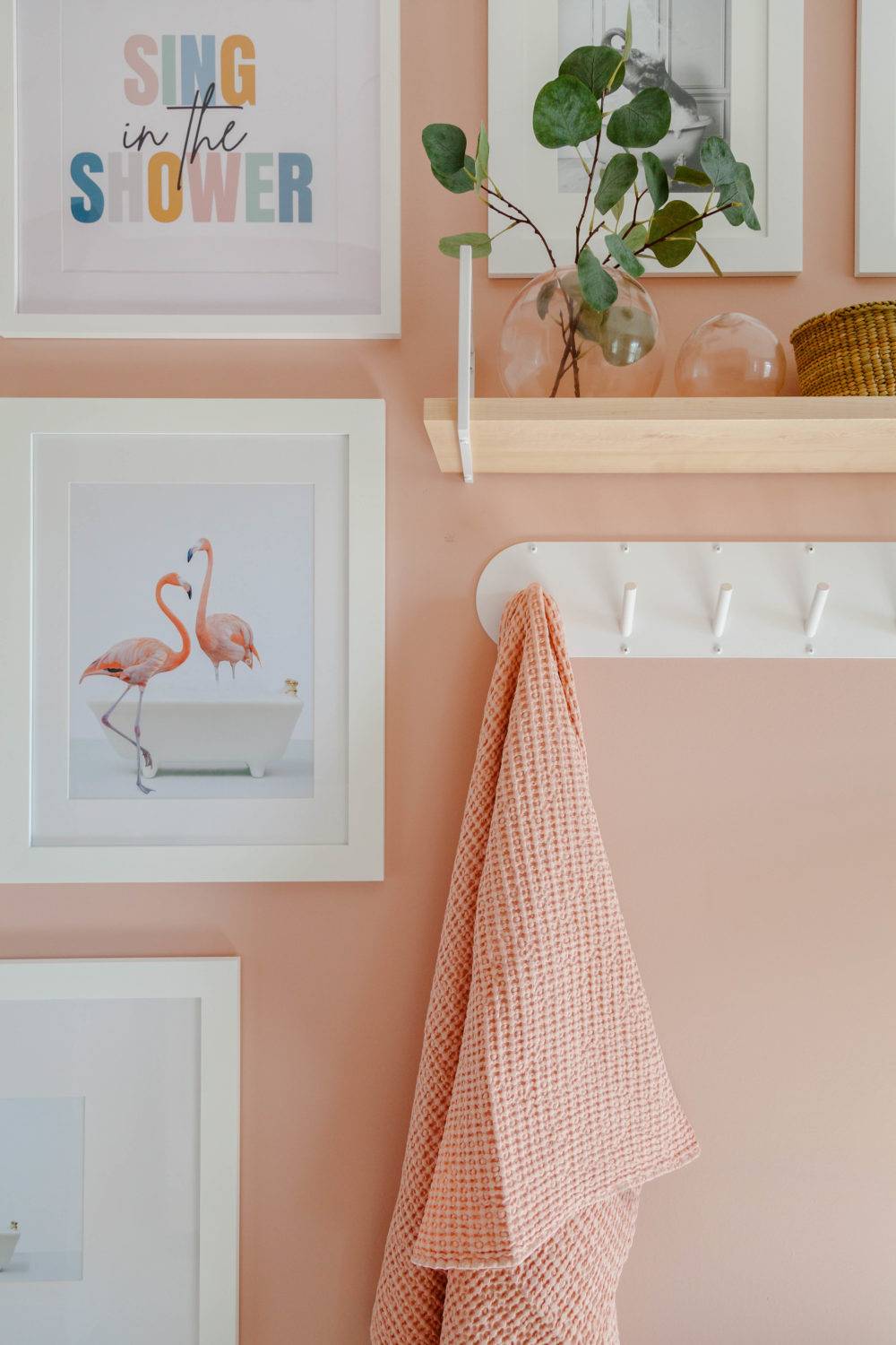 Pink bathroom walls with white artwork and bathroom towel hooks