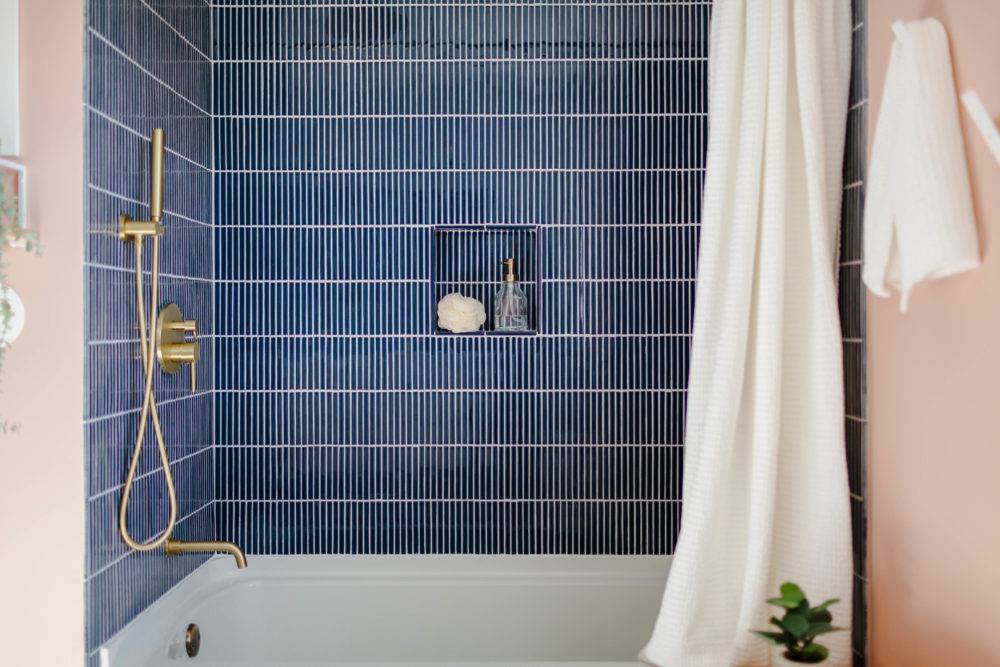 Bathroom with navy blue stacked tile and white shower curtain