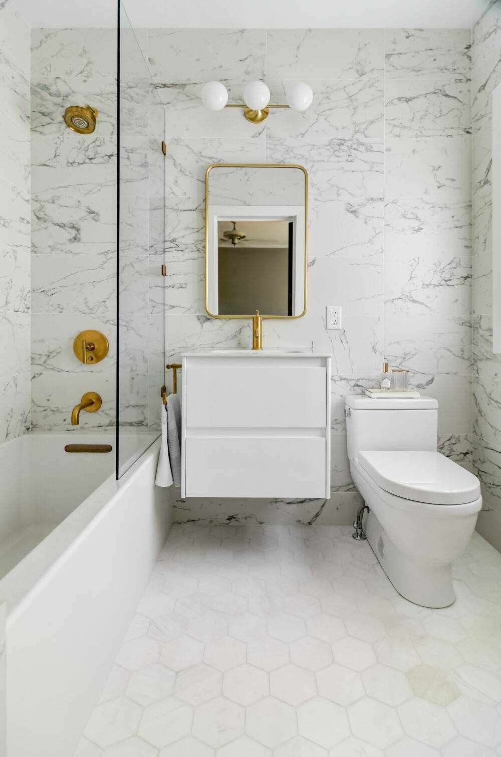 Bathroom white marble-look tile wall and hexagon marble tile floor.