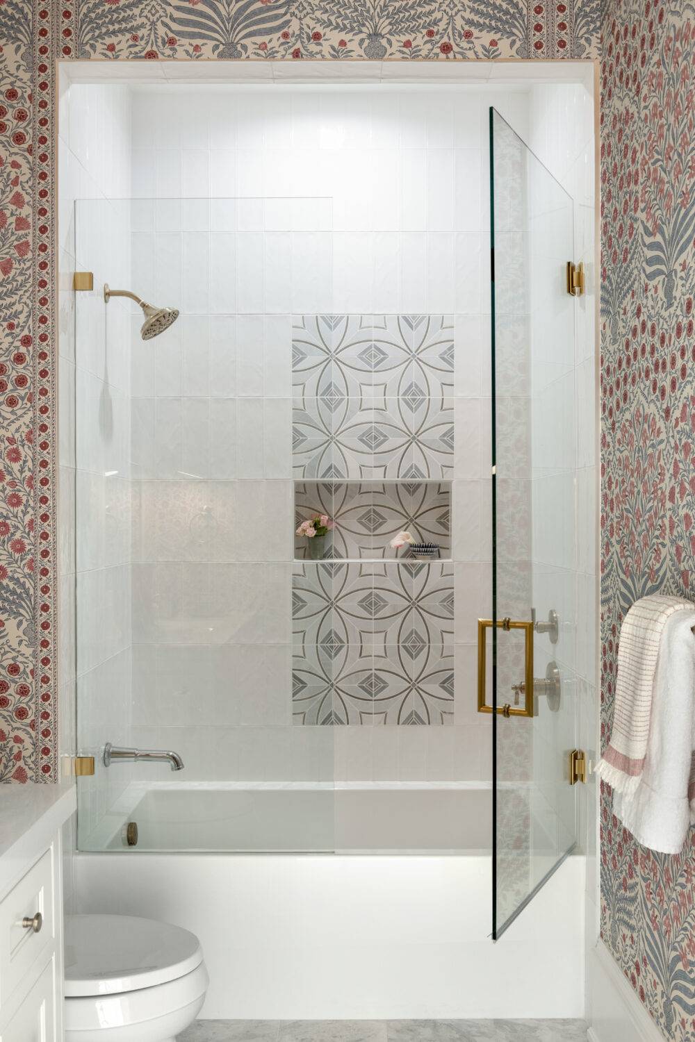 Guest bathroom shower with bold-patterned wallpaper featuring McQueen Grey and Belvar White tile. 