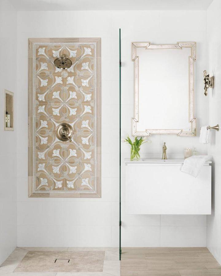 Bathroom area with walk in shower and floating vanity.  Shower and wainscoting tile are rectangular raised glaze white surfaces . Shower wall has a framed out tulip mosaic tile and matching niche. Flooring is marble and limestone tiles in similar tones.