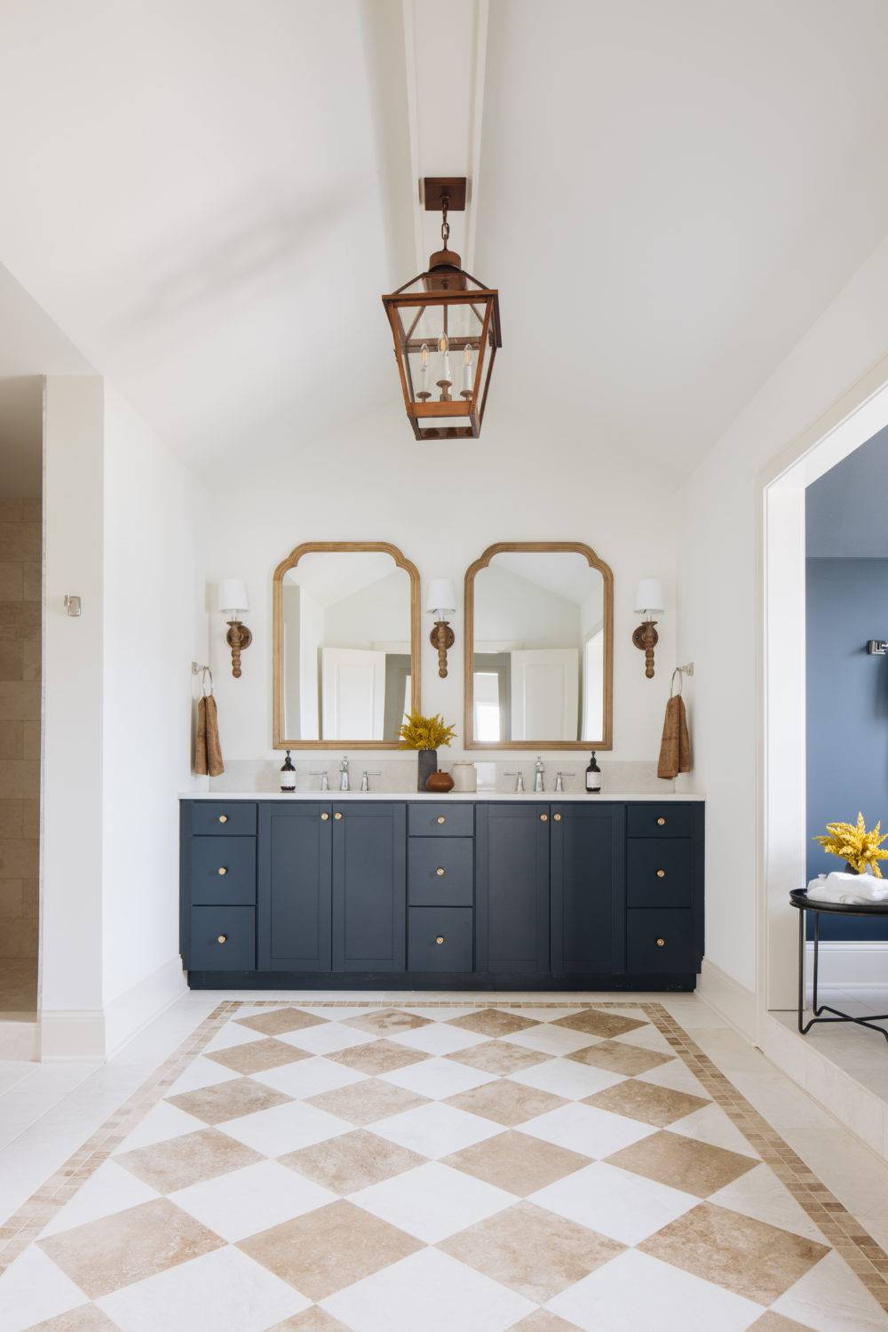 Large bathroom with stone checkerboard floor and navy vanity