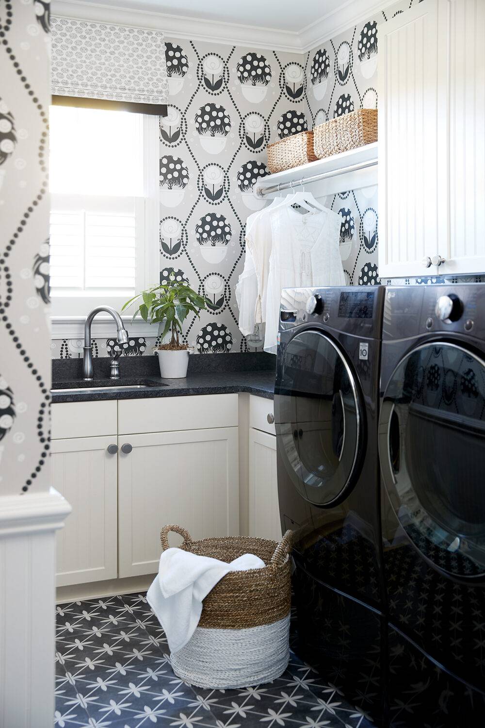 Laundry room with black and white patterned wallpaper and black with white star shapes tile floor. 