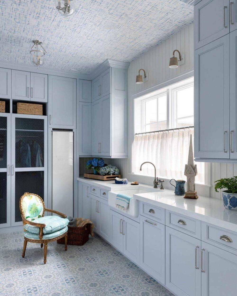 Blue hued laundry room with blue and grey patterned encaustic-look floor tile. 